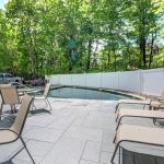 Pool and patio with trees in background.